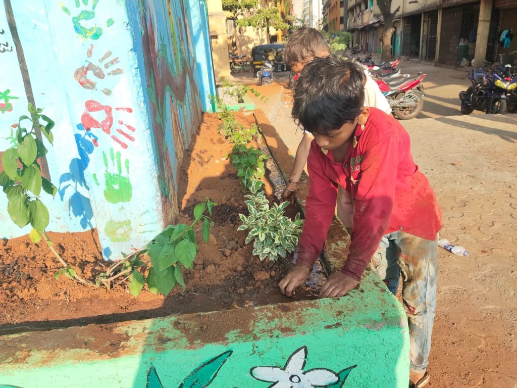 हरियाली के लिए लगाए गए पौधों की देखभाल करते हुए बच्चे
